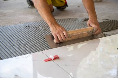 Yapıştırıcı sürüyorum. Seramik beyaz fayanslar tutkal üzerine serpiştirilmiş. 