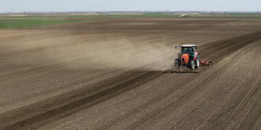 Traktör tarlada çalışıyor, tarlayı ekime hazırlıyor, tarlayı sürüyor.