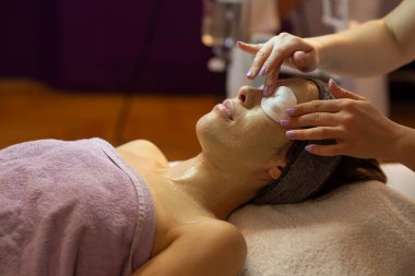 Yüz soyma maskesi, kaplıca güzellik tedavisi, cilt bakımı. Güzellik salonundaki kadın yüz bakımını alıyor. Yan görüş, yakın çekim.