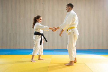 Beyaz judogi giyen genç sarı kuşak judo adamı ve beyaz judogi giyen genç siyah kuşak judo kızı.