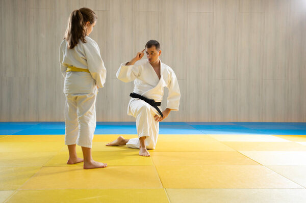 Мастер дзюдо и юная девушка с жёлтым поясом по дзюдо в белых дзюдоидах 