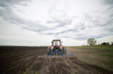 Traktör tarlada çalışıyor, tarlayı ekime hazırlıyor, tarlayı sürüyor.