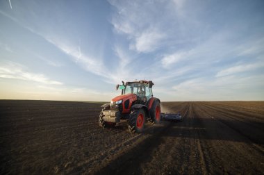 Traktör tarlada çalışıyor, tarlayı ekime hazırlıyor, tarlayı sürüyor.