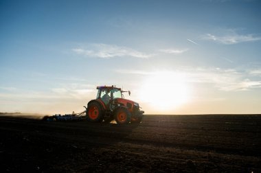 Traktör tarlada çalışıyor, tarlayı ekime hazırlıyor, tarlayı sürüyor.