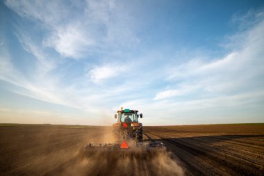Traktör tarlada çalışıyor, tarlayı ekime hazırlıyor, tarlayı sürüyor.
