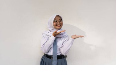 Endonezyalı, gri beyaz üniformalı, kravatlı ve tesettürlü kız lise öğrencileri başlarını tutup aşağıya bakan bir şey hakkında derin düşüncelere dalıyorlar..