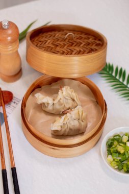 Steamed dumplings shrimp in asian style on white concrete background. Prawn dim sum with green leek and chopstick