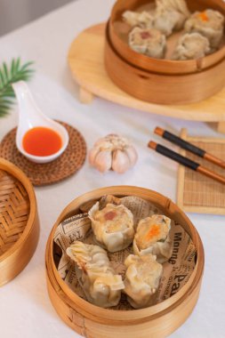 Steamed four flavor dumpling dimsum in traditional bamboo steamer with sauce and green leek. Close up food photography