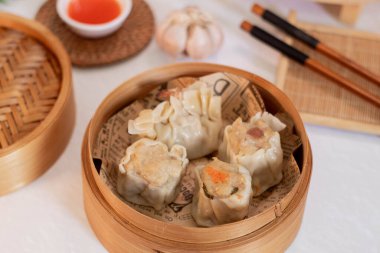 steamed four flavor dumpling dimsum in traditional bamboo steamer with sauce and green leek. Close up food photography