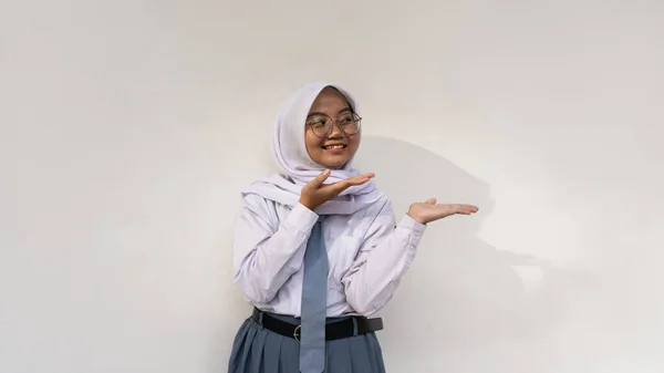 Endonezyalı, gri beyaz üniformalı, kravatlı ve tesettürlü kız lise öğrencileri başlarını tutup aşağıya bakan bir şey hakkında derin düşüncelere dalıyorlar..