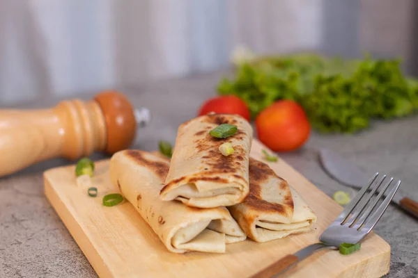 three mini kebabs filled with meat are stacked on a cutting board with a gray concrete background