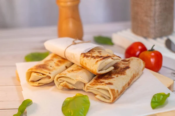 Fourmini kebabs filled with meat are stacked on a cutting board against a white wooden background