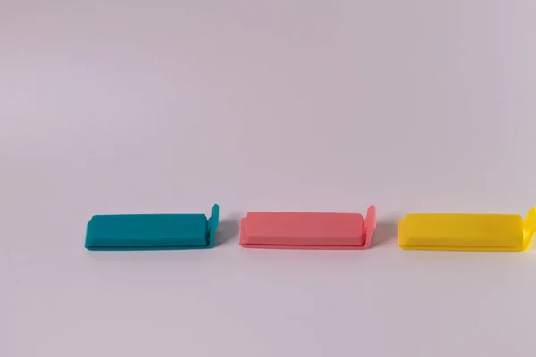 Composition of blue-pink-yellow plastic food bag clippers isolated on a white background. mini clip plastic food
