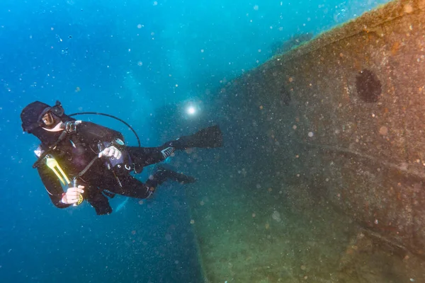 scuba divers exploring a shipwreck underwater