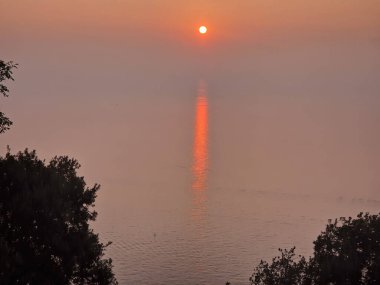 Gün batımı kızıl güneş denizin üzerinde iz bırakır.