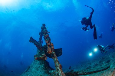 Scuba divers explores propeller of sunken shipwreck dive clipart