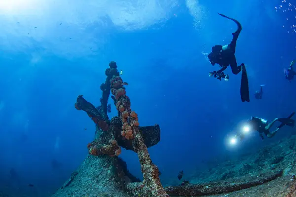 stock image Scuba divers explores propeller of sunken shipwreck dive