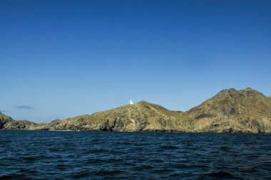 Marguerite Adası kıyısındaki Bahia Körfezi Magdalena Kanalı 'nda beyaz bir deniz feneri. Baja California' da Pasifik Okyanusu 'ndaki volkanik kayaların üzerinde.