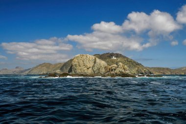 Marguerite Adası kıyısındaki Bahia Körfezi Magdalena Kanalı 'nda beyaz bir deniz feneri. Baja California' da Pasifik Okyanusu 'ndaki volkanik kayaların üzerinde.
