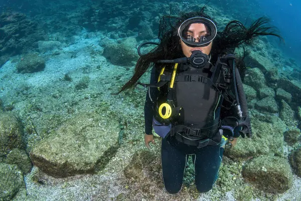 A beautiful black long hair latina scuba diver diving underwater
