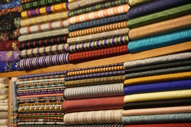 İstanbul Çarşısı 'nda çeşitli elbise ve kumaşlar Türk kültürünün zengin ve renkli duvar halısını gözler önüne seriyor.