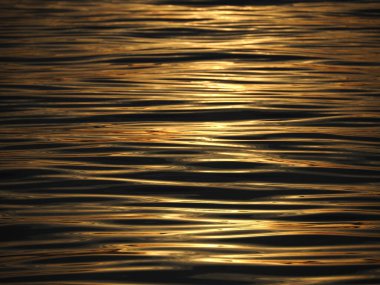 Altın güneş ışığı gün batımında denize yansıyor.