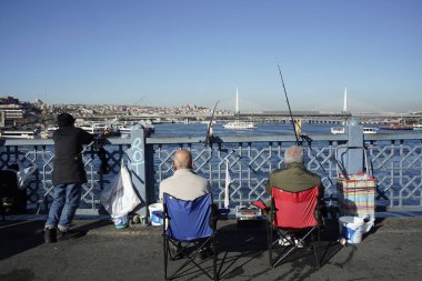 İSTANBUL, TURKEY - 5 HAZİRAN 2024 Galata Köprüsü 'nde balık tutan insanlar. Elinde olta olan bir sürü insan..