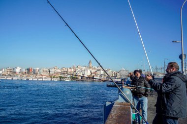 İSTANBUL, TURKEY - 5 HAZİRAN 2024 Galata Köprüsü 'nde balık tutan insanlar. Elinde olta olan bir sürü insan..
