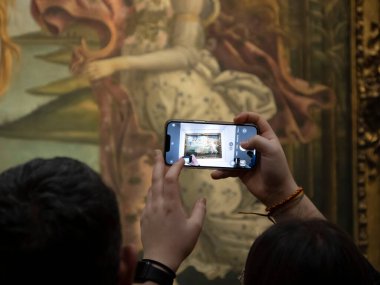 FLORENCE, İTALYA - 24 Mart 2024 - Uffizi Galerisi Sandro Botticelli 'nin Venüs' ün doğumu sırasında akıllı bir sesle fotoğraf çeken turistlerle dolu dünyanın en önemli müzelerinden biri