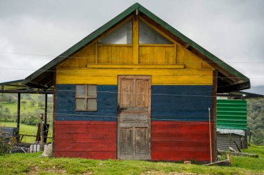 Bogota yakınlarındaki Laguna di Guatavita lagününün kırsal tepesinde bir Kolombiya bayrağı ahşap evi boyadı.