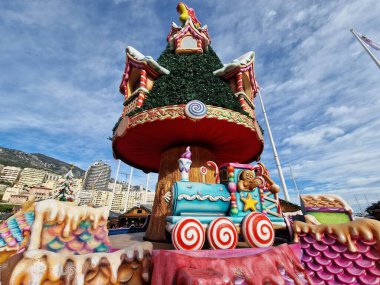 MONTE CARLO, MONACO - 22 Aralık 2024 - Geleneksel Noel pazarı xmas ağacı ve Monte Carlo limanının önündeki bölgeyi süsleyen şenlikli süslemeler, Noel ruhu ve ksenlerin mevsimsel cazibesi