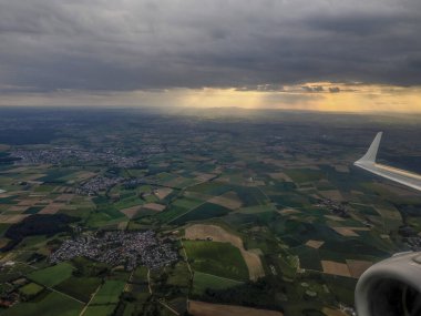 Frankfurt yakınlarındaki bölge, hava alanına inmeden önce gün batımında uçak penceresinden hava manzaralı.