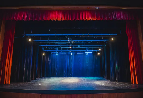 Theater stage with red curtain and yellow blue lights giving warm and cold tones