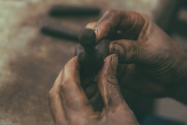 Zanaatkar, görkemli süsler yapmak için elleriyle kil işliyor..
