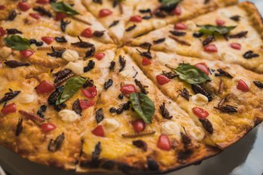 Çekirgeler, solucanlar, çinçullar, meyve suları ve chicatanas gibi böcekli zanaatkar pizzaya yanında vişneli domates, ıspanak ve üç peynir eşlik ediyor..