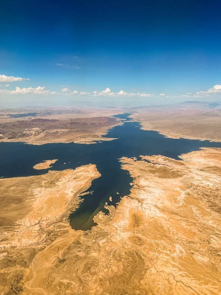 Aerial photography of the Nevada desert, United States, you can see the mountains, the desert plain, a lake with a river, the clouds and the sky.