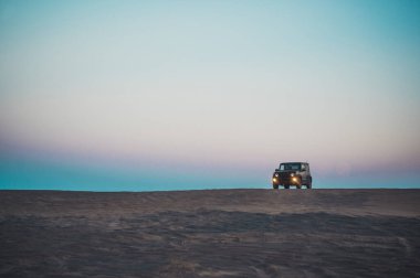 Kum tepelerinde gün batımı, arazi aracıyla.