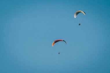 Yükseklerden süzülen paragliding bulutları ve mavi gökyüzünü görebilirsin.