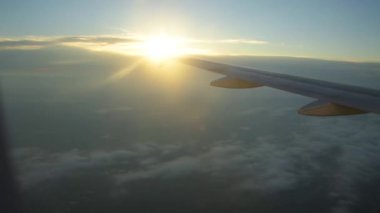 Bir uçağın penceresinden kaydedilen video geziyi gösteriyor. Bulutları, gökyüzünü, uçağın kanadını ve günbatımını görebilirsiniz..