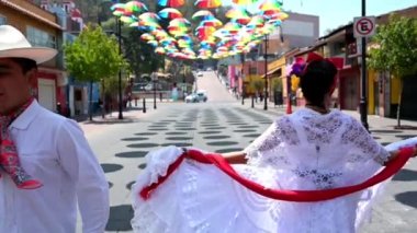 Meksikalı halk dansçılarının yavaş çekimde HD videoları, renkli şemsiyeler altında Meksika kasabalarından geleneksel kıyafetler giyerek bir gösteri yapıyorlar..