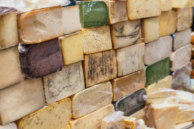 Gouda, parmesan, manchego, keçi mavisi, baharatlı ve markette tezgahları olan peynirlerden oluşan bir duvar..