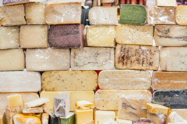 Gouda, parmesan, manchego, keçi mavisi, baharatlı ve markette tezgahları olan peynirlerden oluşan bir duvar..