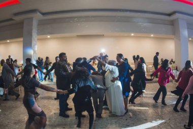 Tipik bir Meksika düğününün fotoğrafları. Gelin, damat ve konuklar arka planda renkli ışıklarla geleneksel Vivora de la Mar dansı yapıyorlar..