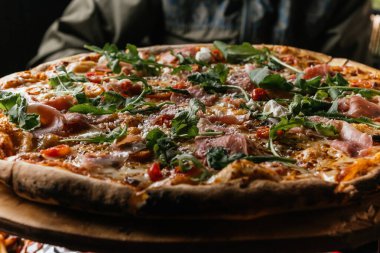 Serrano jambonlu Margherita Pizzası malzemelerini, peynirini, domatesi ve güzel otlarını gösteriyor..