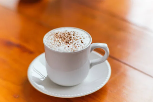 Cappuccino coffee with cinnamon powder, served in a white cup, freshly ground from the recent harvest.