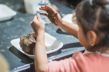 Kil atölyesinde kil kalıbı döşeyen eller insanlara figürler yaratmak için malzemeyi nasıl şekillendireceğini öğretir..