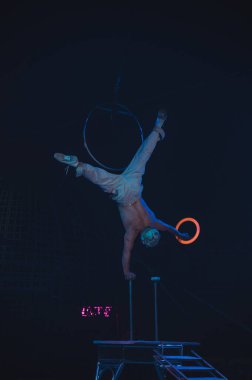 Sirk akrobatları fosforlu halkalarla hokkabazlık yaparken maske takıyor..