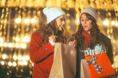 Arkadaşlar bayram hediyesi görünce eğleniyor ve şaşırıyor. Kış kıyafetleri giyip Noel alışverişi yapıyorlar. Arka plandaki ışıklar kocaman bir Noel ağacı..