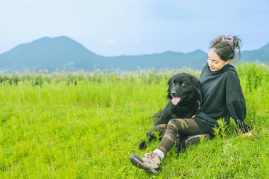 Yeşil tarlada köpeğiyle eğlenen güzel bir kızın hem oynayıp hem gülümseyen hem de eğlenen.