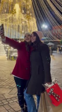 Arkadaşlar selfie çekerken, kış kıyafetlerini giyerken, Noel alışverişi yaparken, çantaları hediyelerle doluyken, arka plandaki ışıklar dev bir Noel ağacı gibi..